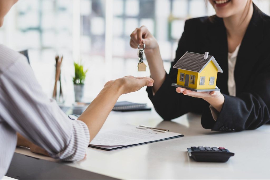 Makelaar overhandigt huissleutels aan een koper tijdens het bespreken van een hypothecaire lening.