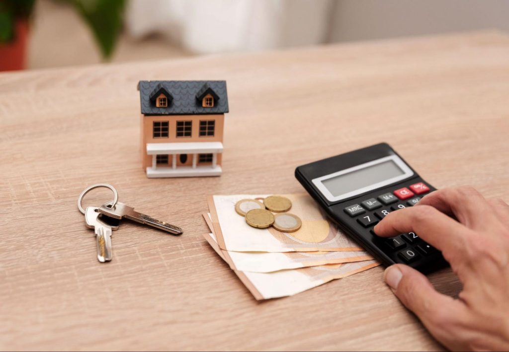 Huissleutel, euro's en rekenmachine op tafel — symbool voor de kosten bij het kopen van een huis